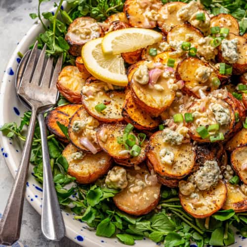 Grilled potato salad with blue cheese vinaigrette on platter with two forks