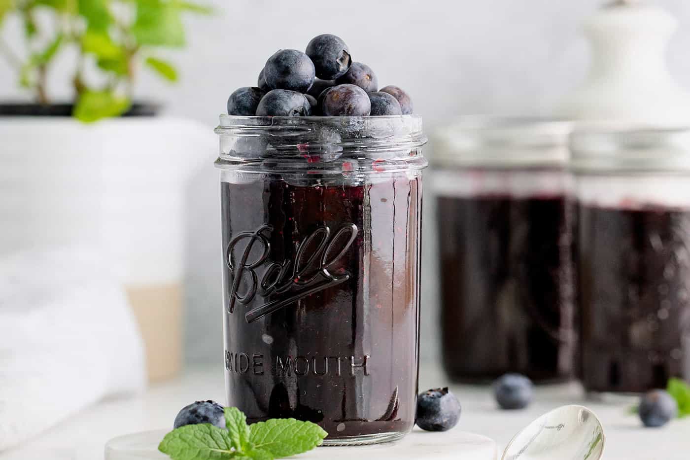 A jar of blueberry jam topped with more blueberries