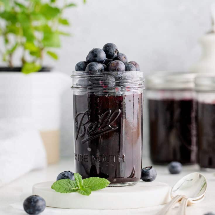 A jar of blueberry jam with more blueberries on top