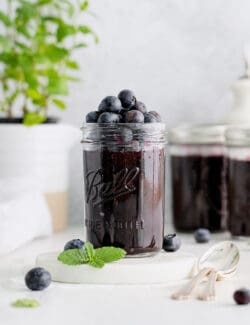 A jar of blueberry jam with more blueberries on top
