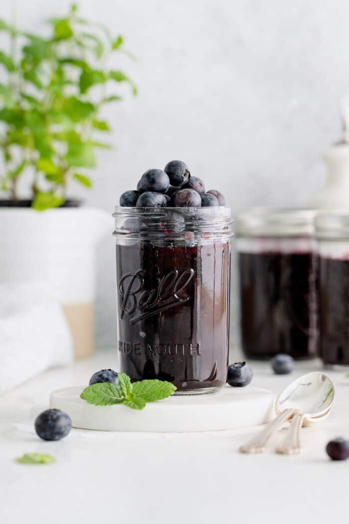 A jar of blueberry jam with more blueberries on top