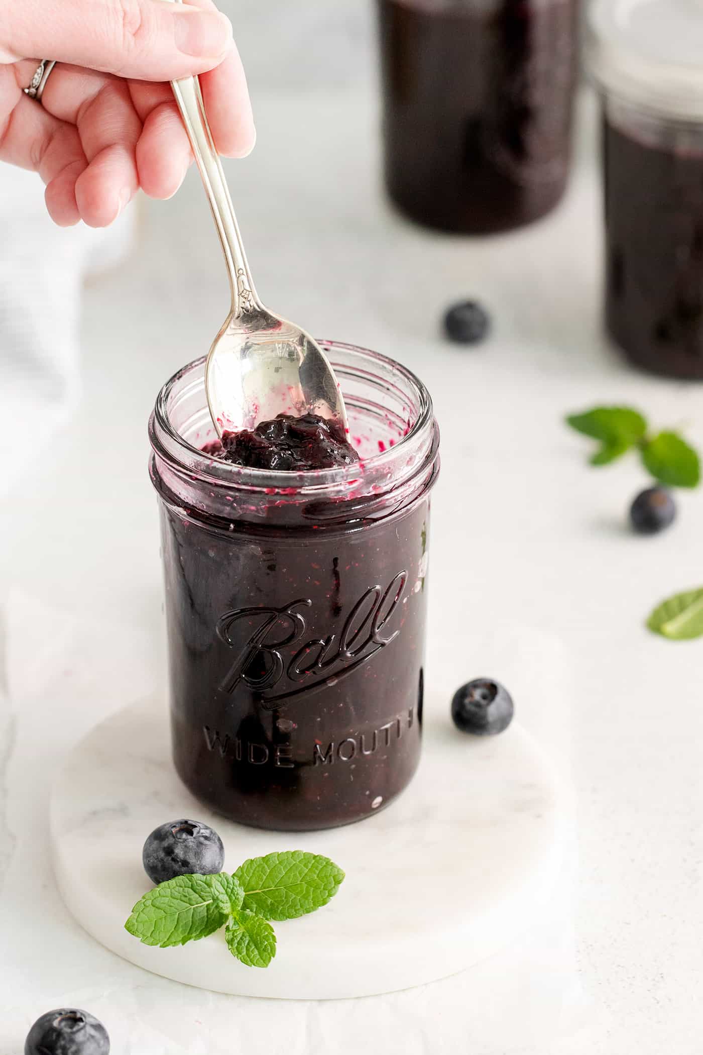 A hand holding a spoon in a jar of jam