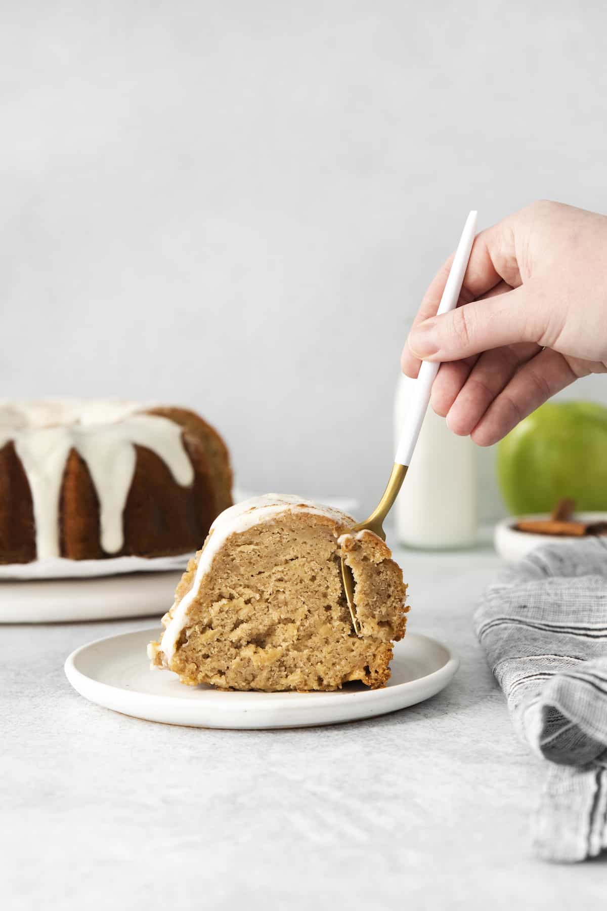 Hand with a fork, taking a bite out of a slice of apple cake