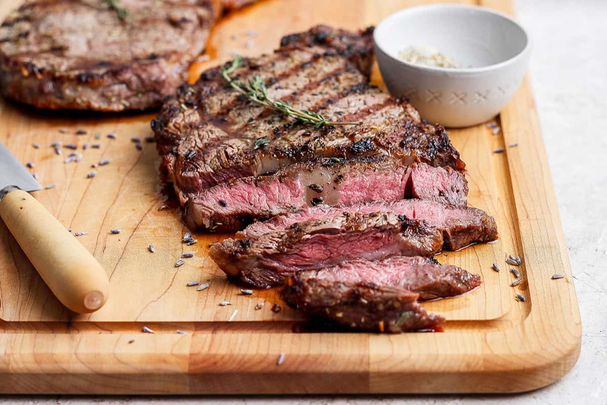 Sliced grilled ribeye steak on cutting board.