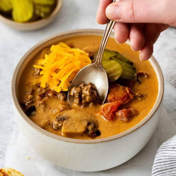 A spoon in a bowl of cheeseburger soup