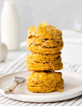 Four pumpkin biscuits stacked on a white plate