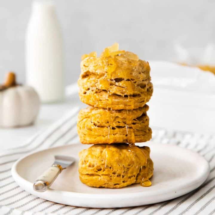 Four pumpkin biscuits stacked on a white plate