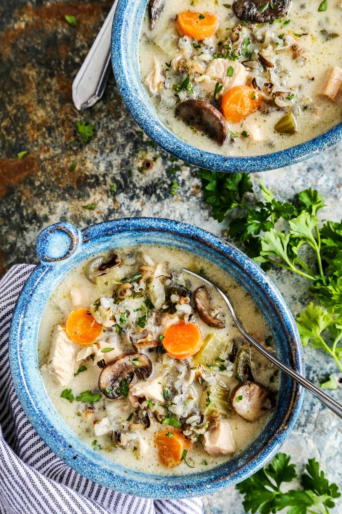 Overhead view of two blue bowls of chicken wild rice soup.