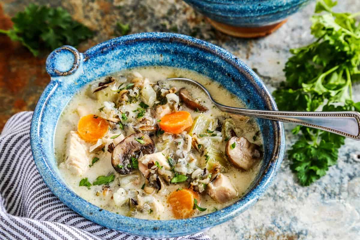 Chicken wild rice soup in a blue bowl with a spoon.