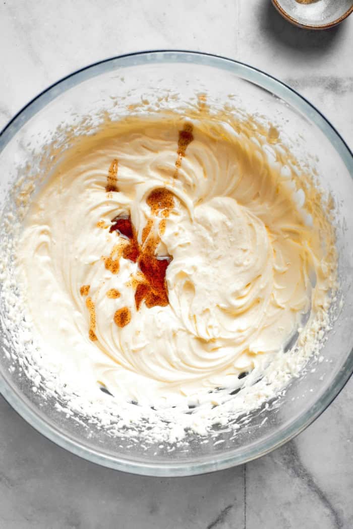 Vanilla addd to cream cheese frosting in bowl