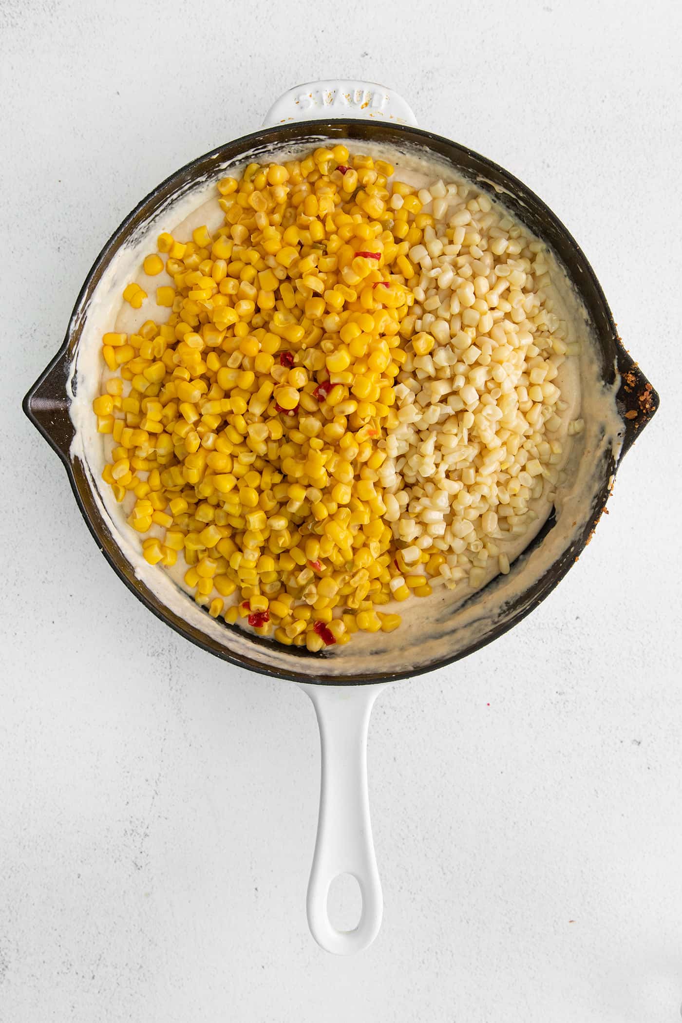 Canned corn in a cast iron skillet with cheese sauce