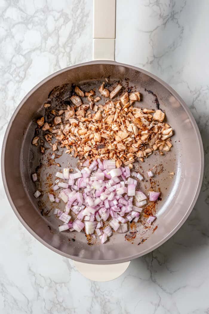 Shallots and mushroom stems in skillet