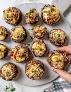 Hand pulling stuffed mushroom from serving board
