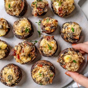 Hand pulling stuffed mushroom from serving board
