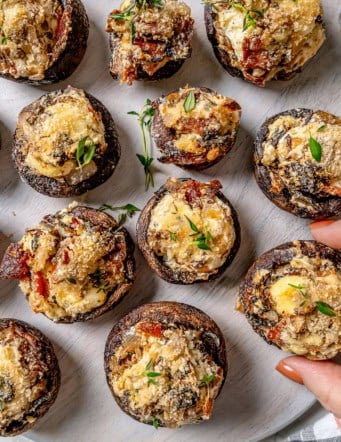 Hand pulling stuffed mushroom from serving board
