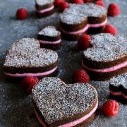 Close-up of heart shaped brownies with raspberry buttercream and a dusting of powdered sugar.