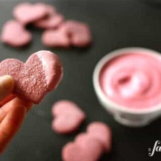 A heart shaped cookie dipped in pink frosting.