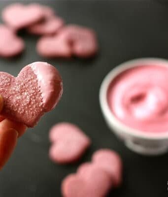 A heart shaped cookie dipped in pink frosting.