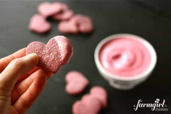 A heart shaped cookie dipped in pink frosting.