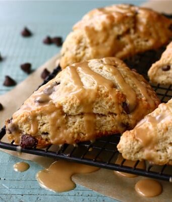 Chocolate chip scones with peanut butter drizzle on a cooling rack