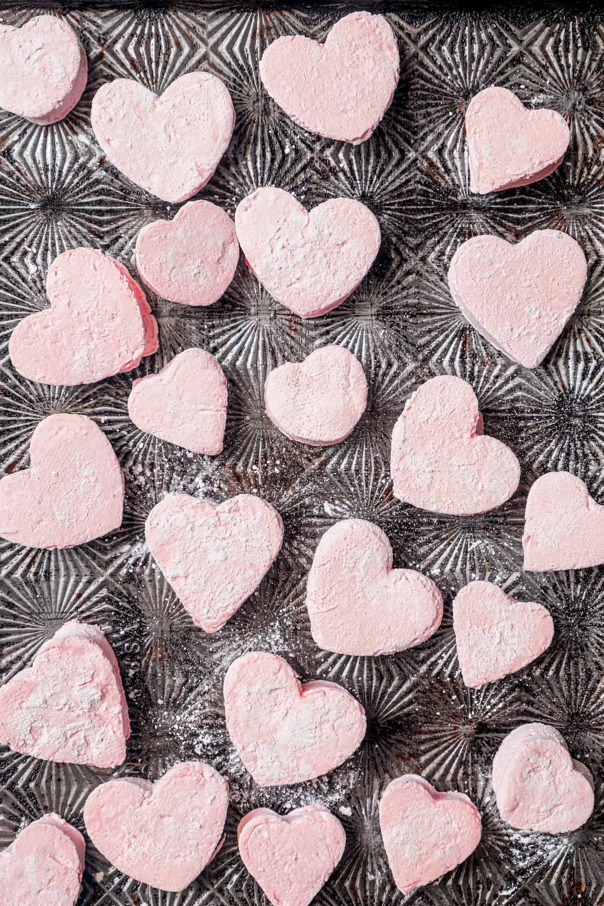 Various sizes of heart marshmallows on baking sheet