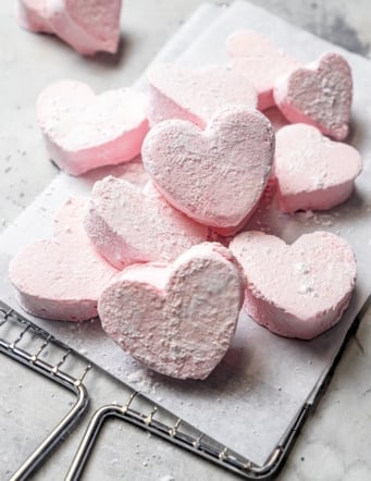 Pile of fluffy marshmallow hearts on parchment-lined wire rack