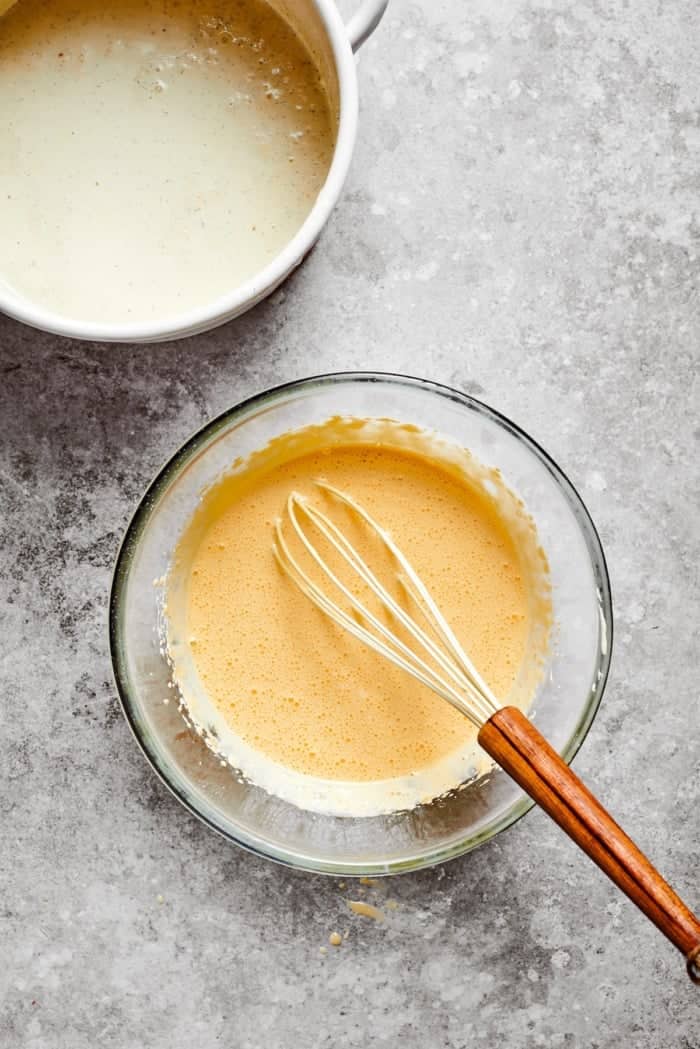 The silky custard in this Almond Vanilla Crème Brûlée lies beneath a glorious caramelized top. An elegant dessert that's surprisingly easy! Whisking custard in glass bowl.