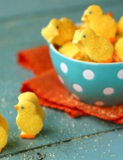Yellow marshmallow chicks sprinkled with sugar in a blue bowl