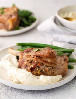 A plate of stuffed pork chops with mashed potatoes and green beans