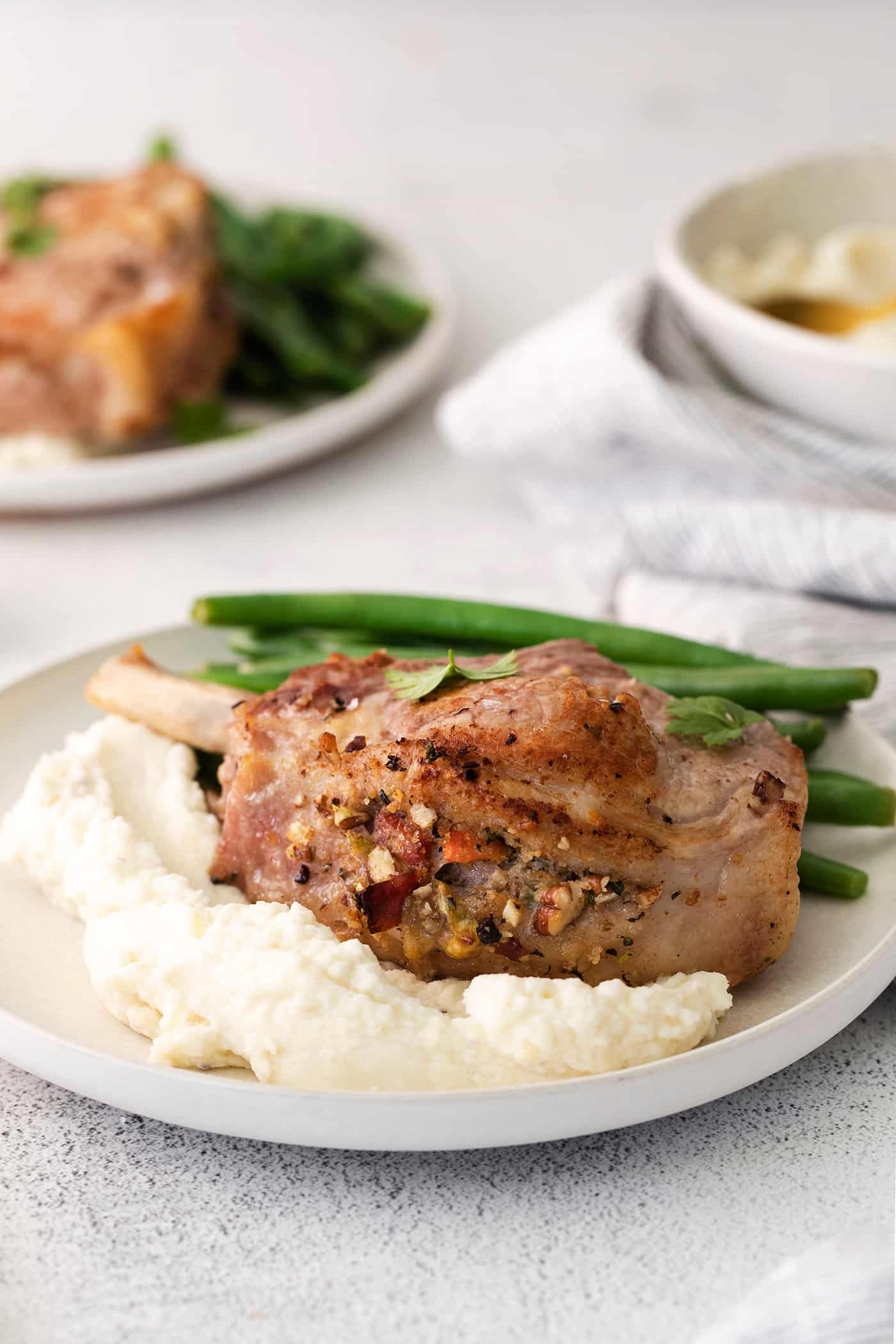 A plate of stuffed pork chops with mashed potatoes and green beans