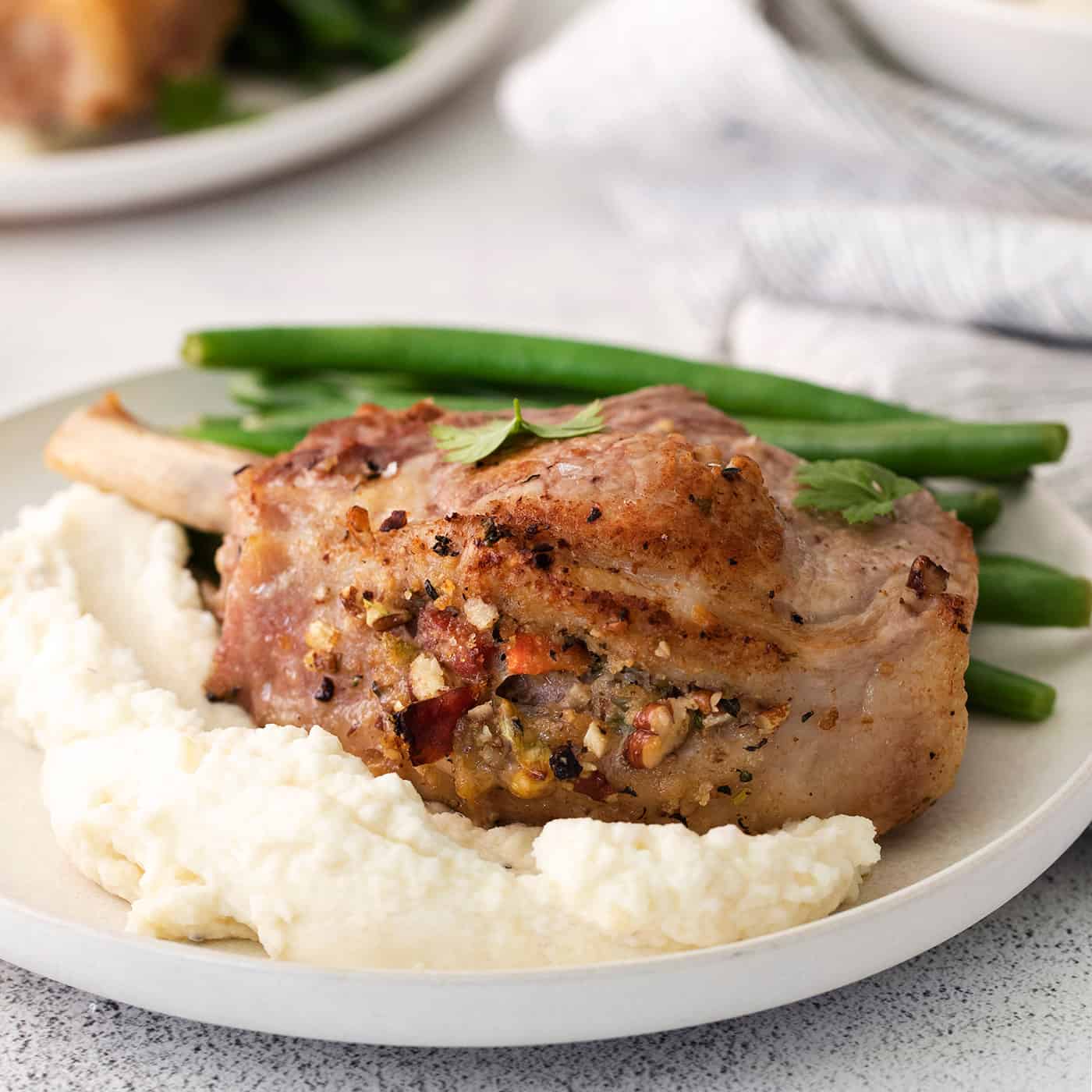 A plate of stuffed pork chops with mashed potatoes and green beans