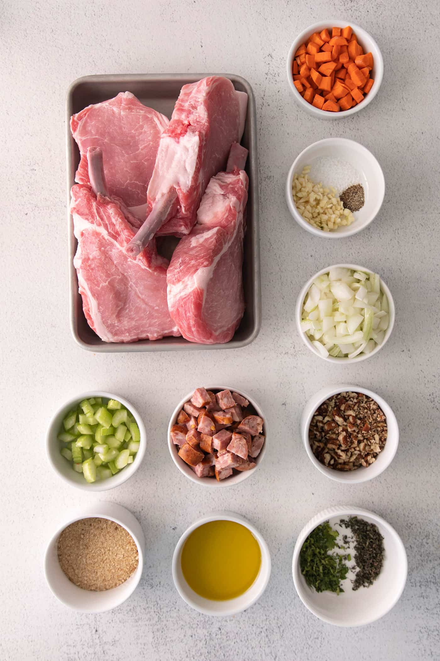 Overhead view of pork chops with andouille and pecan stuffing ingredients