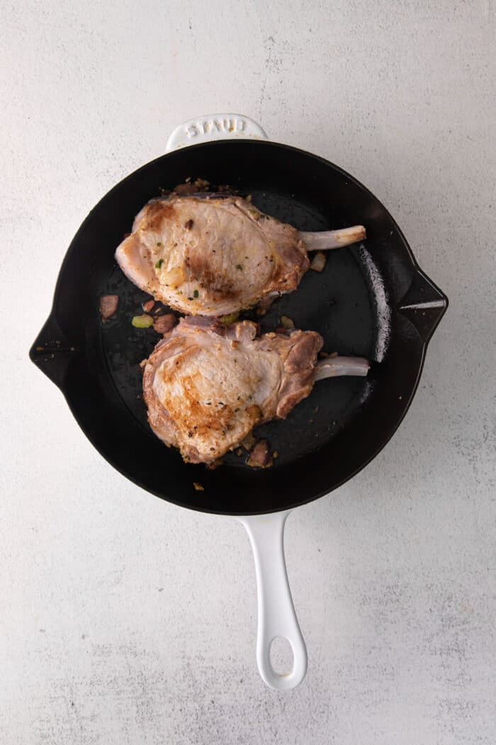 Two stuffed pork chops in a cast iron skillet