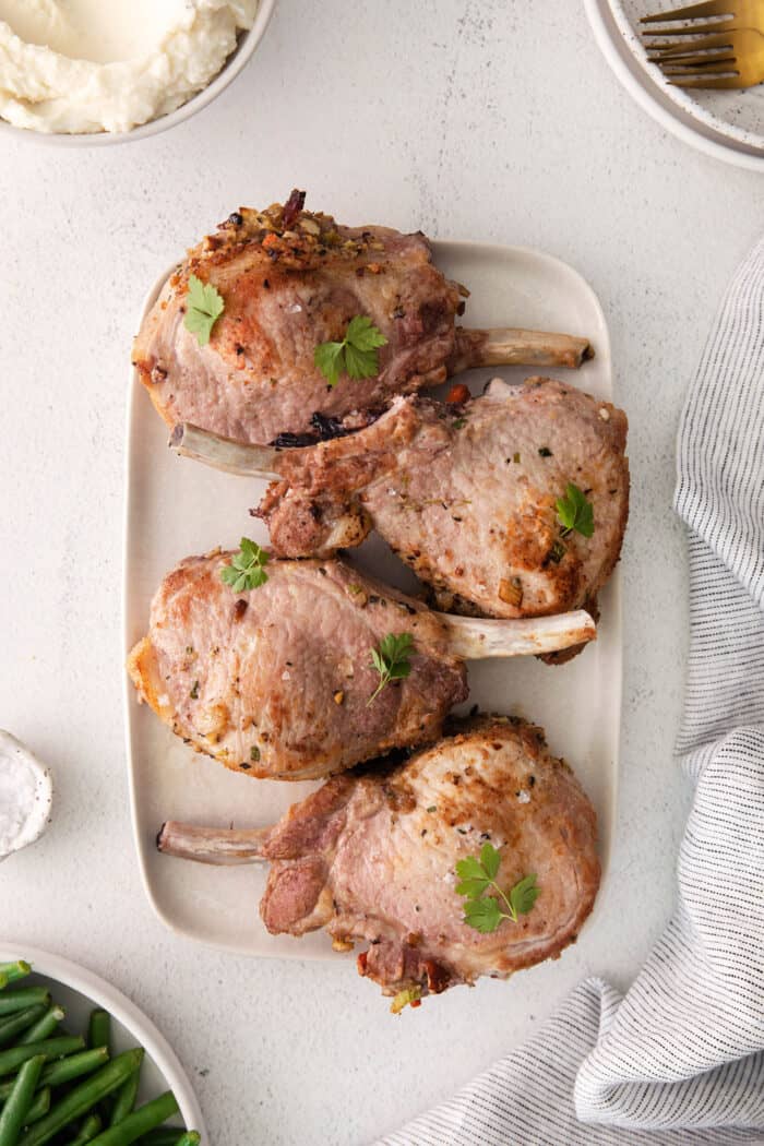 Overhead view of four stuffed pork chops on a white platter