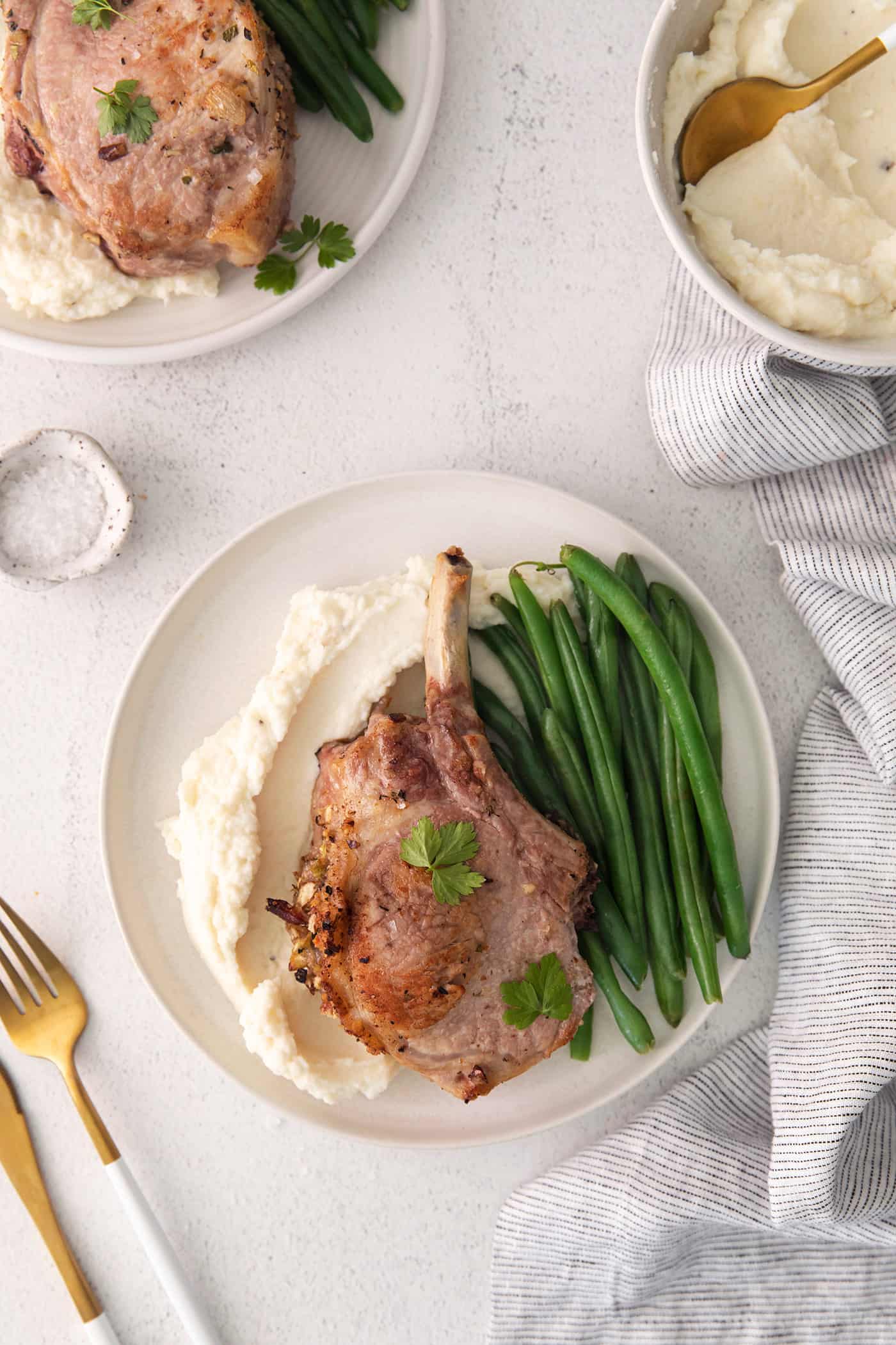 Overhead view of a stuffed pork chop with mashed potatoes and green beans
