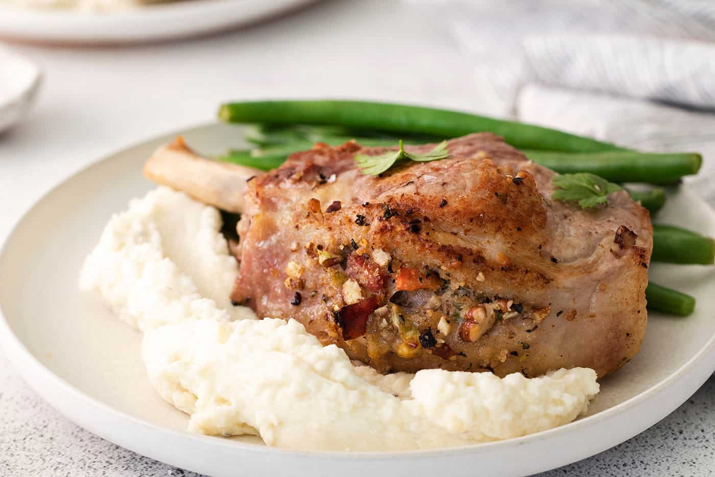 Mashed potatoes, green beans and a stuffed pork chop on a plate