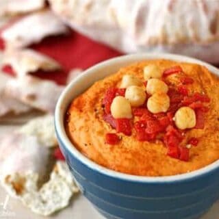 a bowl of red pepper hummus and pita bread