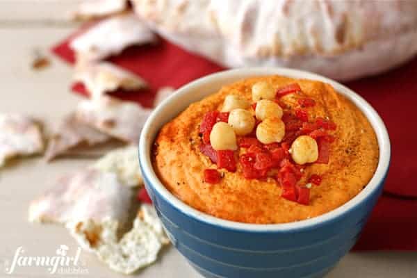 a bowl of red pepper hummus and pita bread