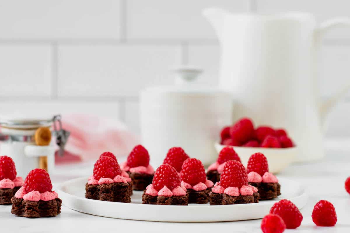 Several brownie bites with raspberry frosting on a plate