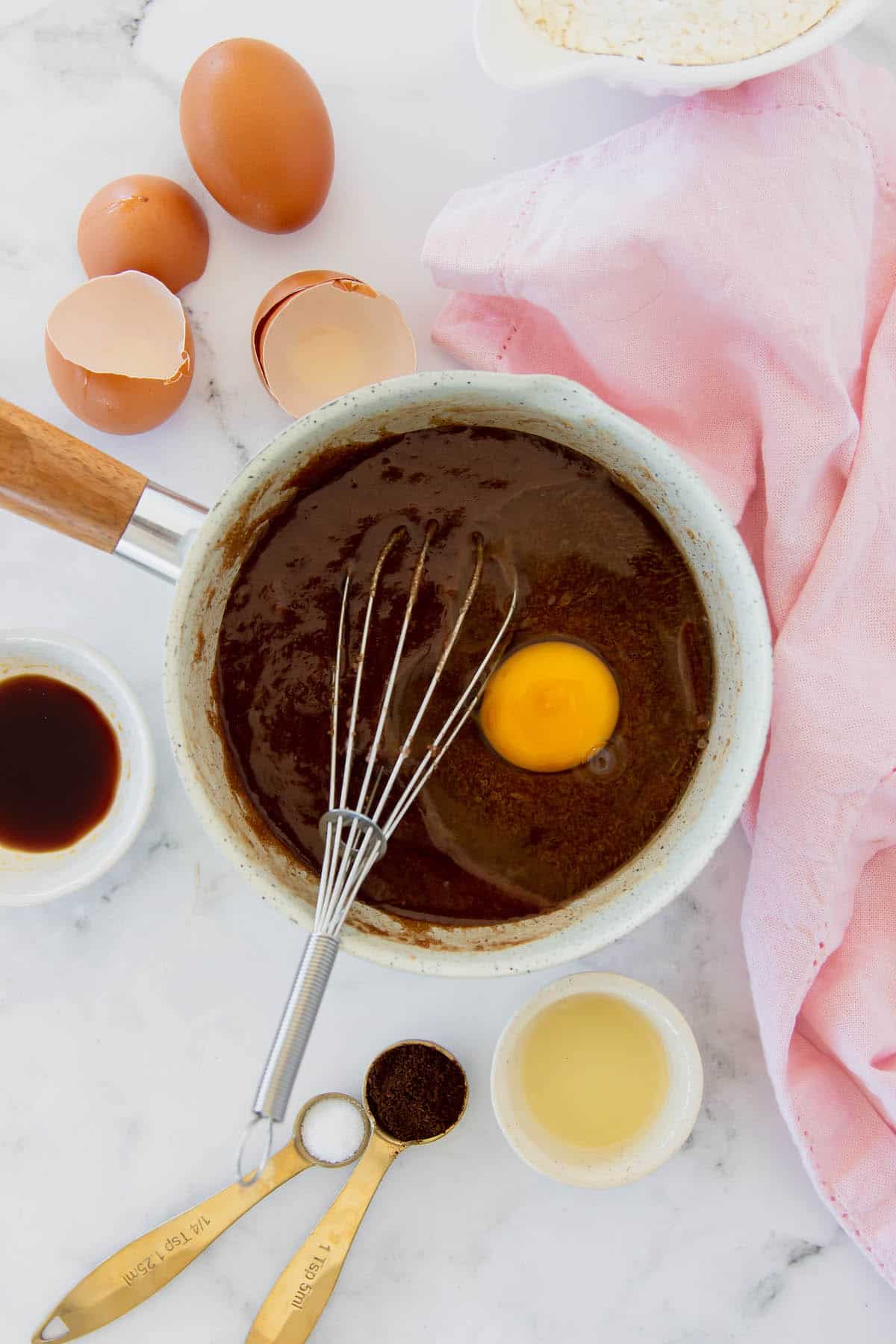 An egg being whisked into melted chocolate