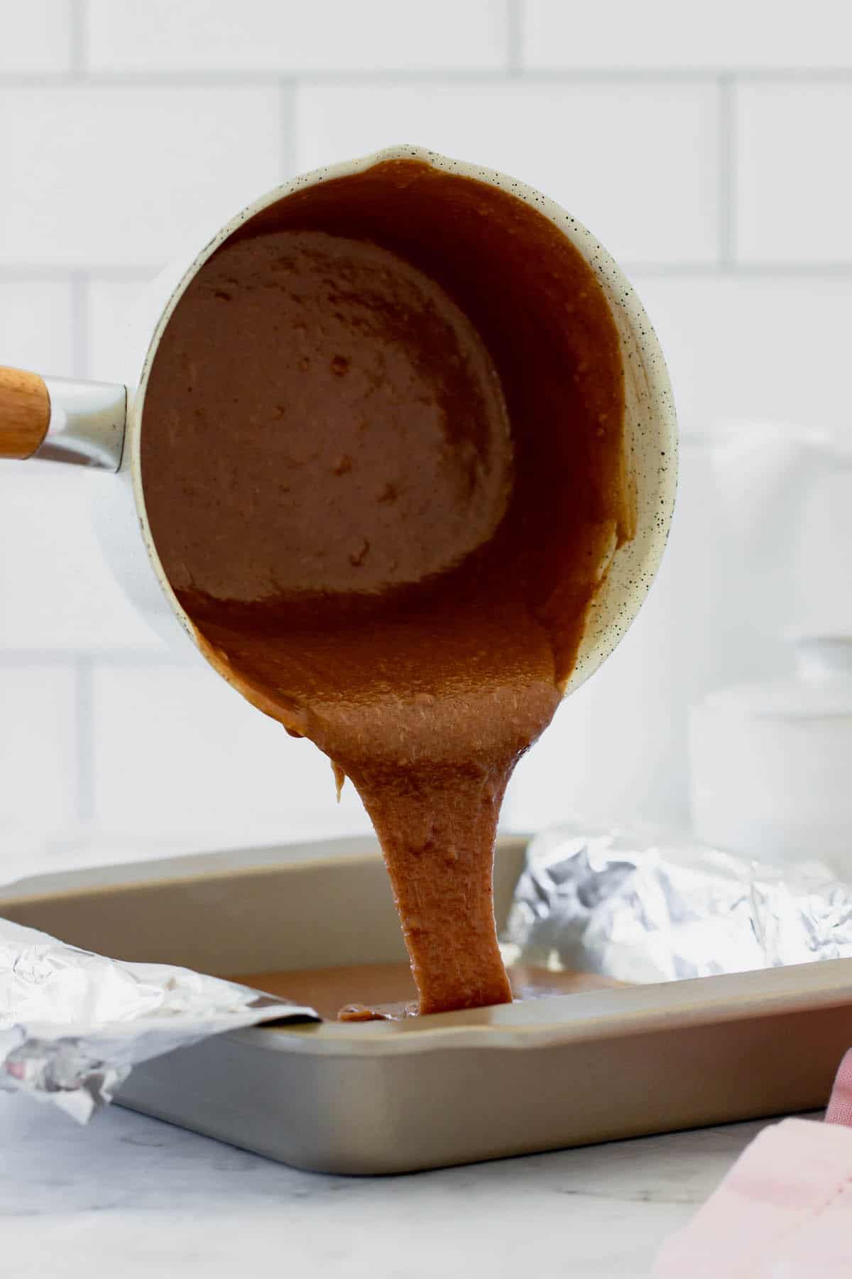 Brownie batter being poured into a baking pan