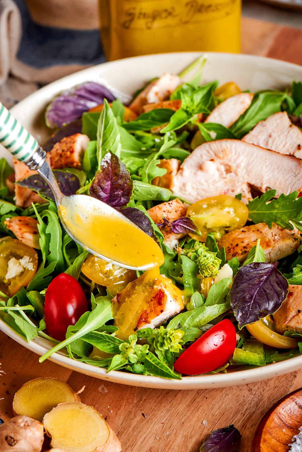 Spooning ginger dressing onto salad.