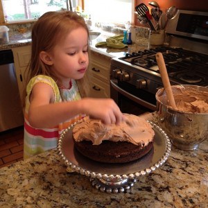 a young girl frosting a cake