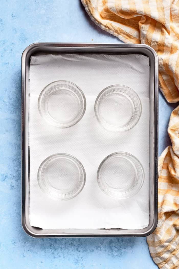 Overhead view of custard cups in pan lined with paper towels