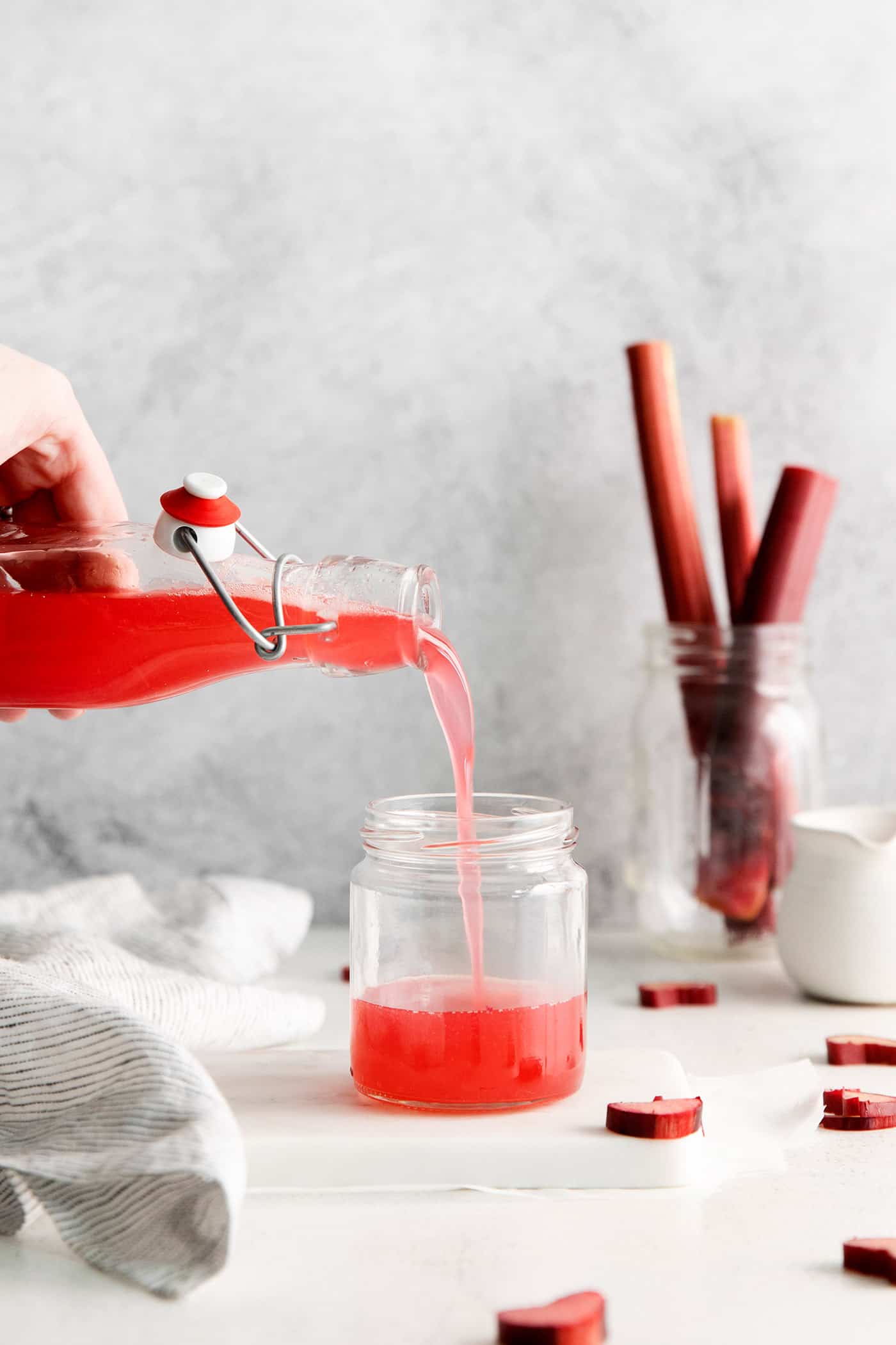 Rhubarb syrup being poured into a small jar