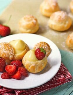 a plate with filled cream puffs and fresh strawberries