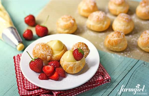 a plate with filled cream puffs and fresh strawberries