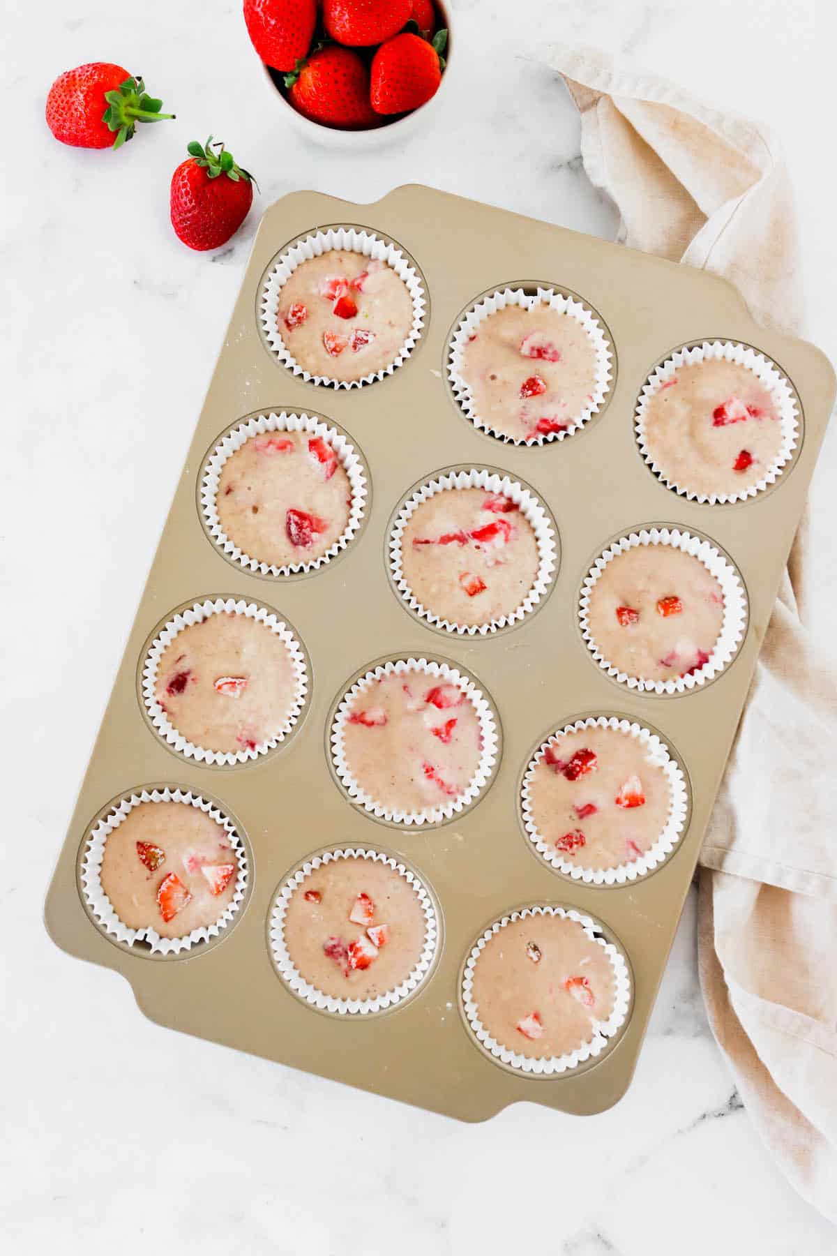 A muffin tin full of strawberry muffin batter