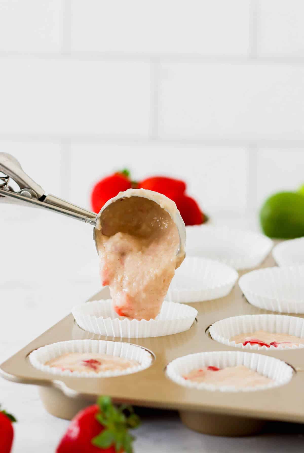 Muffin batter being scooped into a muffin tin