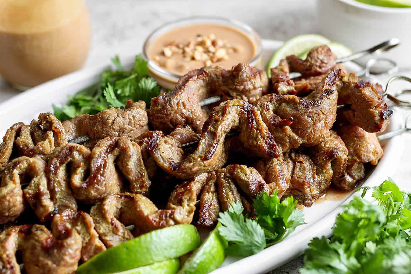 Coconut beef satay on platter with bowl of peanut sauce